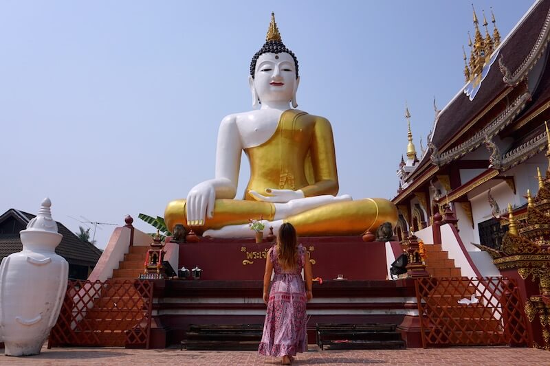 Girl loooks at a buddha statue