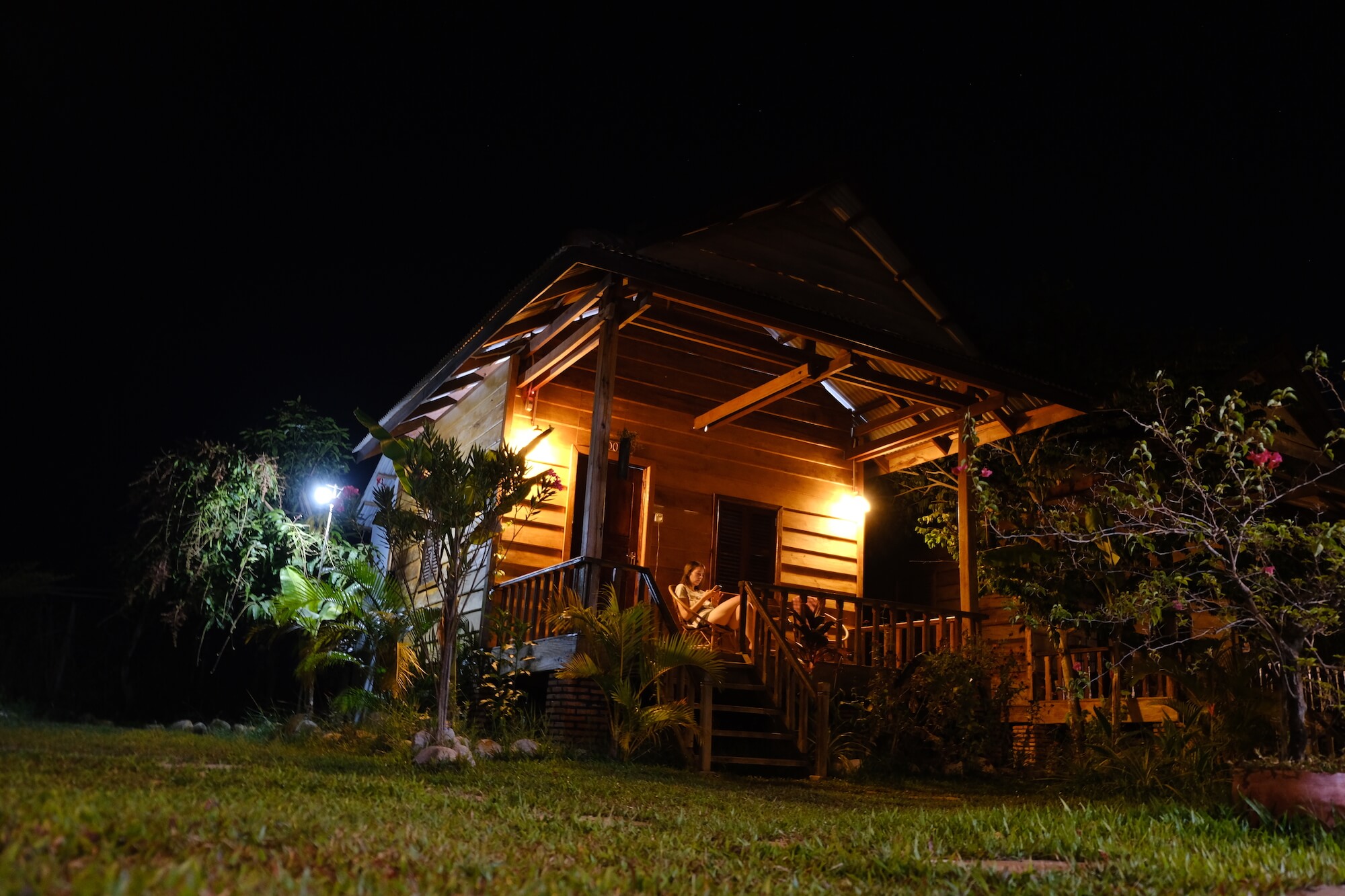 Girl sits on bungalow at night in Kampot