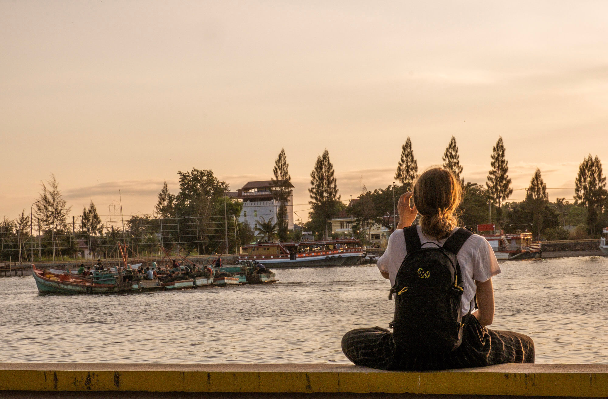 Girl watches boat at sunset in Kampot